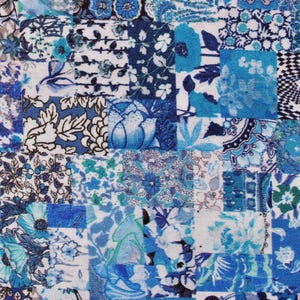 May include: Close-up of a patchwork fabric with a variety of blue and white floral and geometric patterns. The design features squares of different fabrics, creating a textured and visually interesting surface. The color palette includes shades of blue and white.