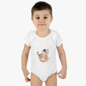 Op de afbeelding: Witte babybody met een afbeelding van het Star Wars-personage BB-8. Het BB-8-ontwerp is oranje, wit en grijs. De body heeft korte mouwen en een drukknoopsluiting.