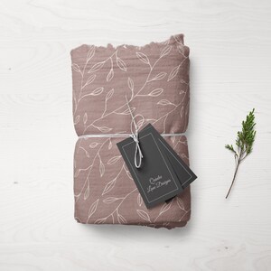 Puede incluir: Un paquete de tela rosa con un patr&oacute;n floral blanco est&aacute; atado con una cuerda blanca y dos etiquetas negras. Las etiquetas tienen texto blanco que dice "Crafted Love Designs".