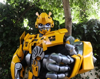 May include: A detailed, yellow and gray Bumblebee costume, featuring intricate mechanical details and glowing blue eyes. The costume is designed with segmented armor and a robotic aesthetic, perfect for cosplay or themed events.