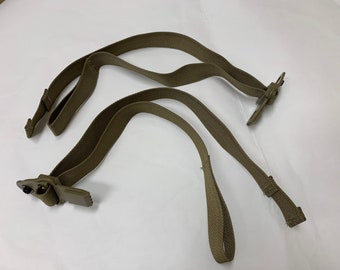Op de afbeelding: Twee beige nylon banden met metalen gespen. De banden zijn ontworpen om te worden gebruikt als draaggreep of schouderband.