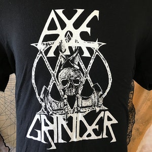 Puede incluir: Camiseta negra con un gráfico blanco de una calavera con un ancla y el texto "Axe Grinder".