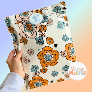 May include: A white poly mailer with a floral pattern in shades of orange, blue, and pink. The mailer has a sticker that says "Happy Mail is Here". The mailer is labeled "Magical Mailers".