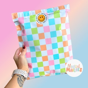 May include: A white poly mailer with a checkered pattern in pink, blue, green, and orange. The mailer has a sticker with a smiley face and the text "Happy Mail You've Got Happy Mail You've Got". The mailer also has a sticker with the text "Magical Mailers".
