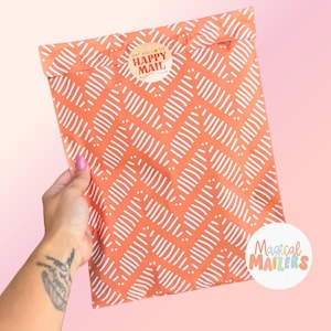 May include: An orange mailer bag with a white zigzag pattern. The bag has a circular sticker that says "Say Hello to Happy Mail." The Magical Mailers logo is visible on the bottom right.