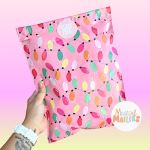 May include: Pink poly mailers with a string of colorful lightbulbs pattern. The mailers have a white sticker that says "You have really great taste!" and a white circle sticker that says "Magical Mailers".
