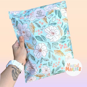 May include: A light blue poly mailer with a floral pattern. The mailer has a sticker that says "Yay! Enjoy the freebie!" and a logo that says "Magical Mailers".