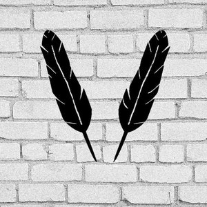 May include: Two black feathers are displayed against a white brick wall background.