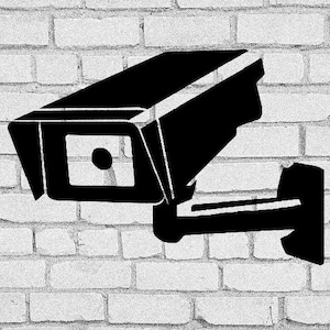 May include: A black security camera mounted on a white brick wall. The camera has a lens with a circular opening.