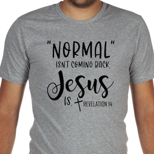 May include: Gray t-shirt with black text that reads "NORMAL" isn't coming back, Jesus is. Revelation 14. The shirt is a crew neck style and is being worn by a person.