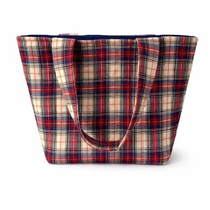 May include: A plaid tote bag in red, white, and blue. The bag has a rectangular shape with a dark blue interior and matching handles. The fabric features a classic tartan pattern.