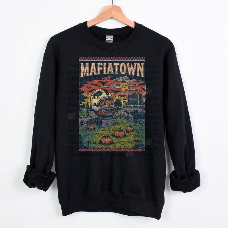 May include: Black sweatshirt featuring a vintage-style graphic with the text "MAFIATOWN." The graphic includes a pumpkin carved like a football helmet, pumpkins, a fence, and a stadium under a sunset sky.
