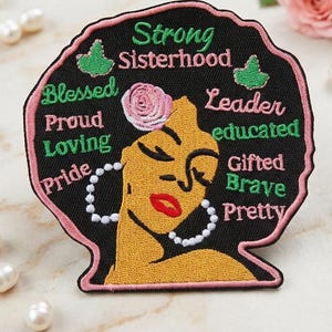 May include: Embroidered patch featuring a stylized woman's face with the words "Strong Sisterhood", "Blessed", "Proud", "Loving", "Pride", "Leader", "Educated", "Gifted", "Brave", and "Pretty". The patch has a black background with pink and green accents.
