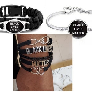 May include: Three black bracelets with silver accents. The bracelets feature the words "Black Lives Matter" and "Love" with an infinity symbol.