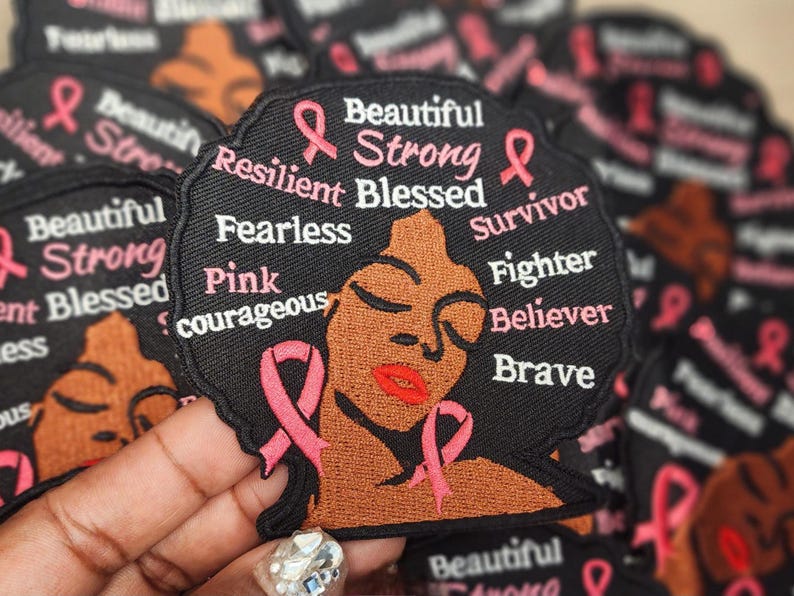 May include: Black and pink embroidered patch with a woman's face and the words "Beautiful Strong Resilient Blessed Survivor Fighter Believer Brave" and "Pink courageous".