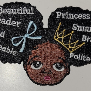 May include: Embroidered patch featuring a cartoon illustration of a Black girl with an afro hairstyle, wearing a gold crown and a blue bow. The afro is surrounded by the words "Princess", "Smart", "Brave", "Polite", "Beautiful", "Leader", "Kind", and "Loveable".