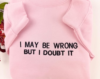 以下が含まれることがあります： 黒い刺繍で「I may be wrong but I doubt it」と書かれたピンク色のスウェットシャツ