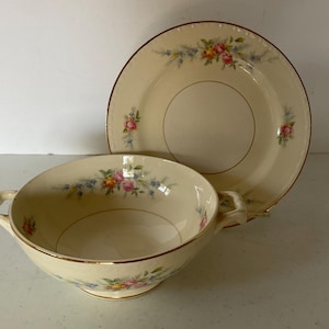 May include: A set of vintage floral patterned soup bowl and saucer. The bowl has two handles and a gold rim. The saucer has a gold rim and a floral pattern.