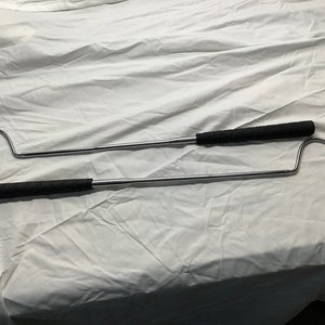Puede incluir: Dos ganchos de metal plateado con mangos de goma negra. Los ganchos están doblados en el extremo y están diseñados para recuperar objetos.