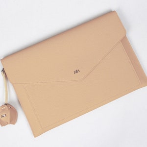 May include: A light beige leather envelope clutch with a small leather tassel. The clutch has a subtle embossed design and the initials "IAI" are embossed on the front.