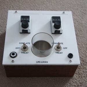 May include: White control panel with two knobs, two switches, and a clear plastic cup. The panel has the text "SIMULATE OFF TREAT" and "SIMULATE OFF TREAT" on the left and right sides, respectively. The text "LMI-LMS0" is printed in the center of the panel.