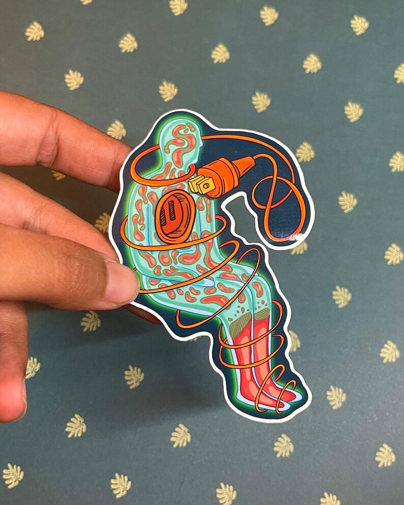 May include: A sticker of a green and orange figure with a cord wrapped around it. The figure is sitting with its legs crossed and has a plug in its chest.