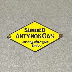 May include: A yellow diamond-shaped sign with black text that reads "SUNOCO ANTY-NOK GAS at regular gas price".