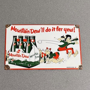 May include: Vintage Mountain Dew metal sign with a cartoon illustration. The sign features a six-pack of Mountain Dew bottles and a cartoon scene with the text "Mountain Dew'll do it fer yew!" The sign has a red border and is marked "MADE IN USA - 61".