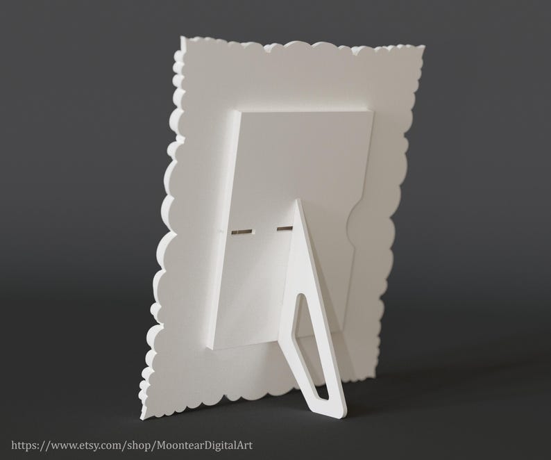 Pu&ograve; includere: Una cornice bianca con un bordo smerlato decorativo e un cavalletto integrato. La cornice &egrave; realizzata in un materiale solido e opaco ed &egrave; progettata per stare in posizione verticale. Il retro della cornice presenta un design geometrico semplice.