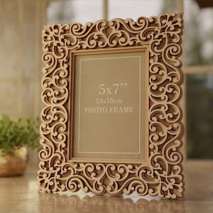 Pu&ograve; includere: Una cornice per foto in legno tagliata al laser con un design ornato e a spirale. La cornice &egrave; adatta per una foto di 13x18cm ed &egrave; etichettata "PHOTO FRAME". Il design include il testo "VECTOR FRAME DESIGN".