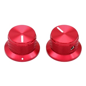May include: Two circular red metal control knobs with a knurled textured side grip and a smooth top surface. Each knob features a single white indicator line on the top and a small circular hole on the side for a set screw to secure the component.