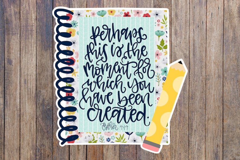 Pu&ograve; includere: Un quaderno blu e bianco con motivo floreale con una citazione che recita "Perhaps this is the moment for which you have been created." La citazione &egrave; in lettere corsive nere e viene attribuita a "Esther 4:14". Una matita gialla con pois bianchi &egrave; accanto al quaderno.