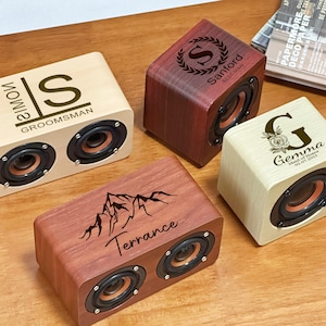 Può includere: Quattro altoparlanti in legno personalizzati con disegni incisi. Un altoparlante ha il nome "Simon" e "Groomsman", un altro "Sanford BEST MAN", un terzo una grafica di montagna e "Terrance", e l'ultimo "Gemma" e "Maid of Honor".