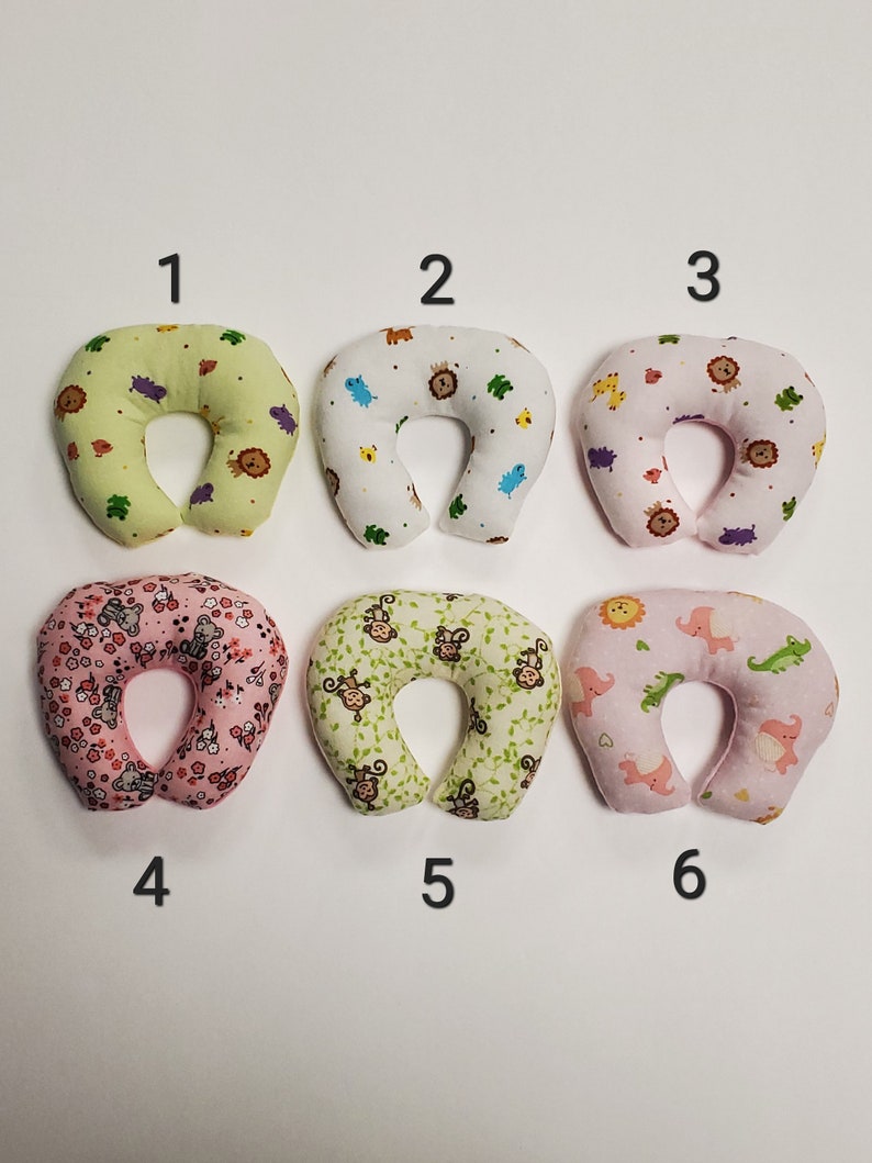 K&ouml;nnte beinhalten: Sechs verschiedene Nackenst&uuml;tzkissen f&uuml;r Babys mit verschiedenen Tiermotiven. Die Kissen sind in hellgr&uuml;n, wei&szlig;, rosa und hellrosa.