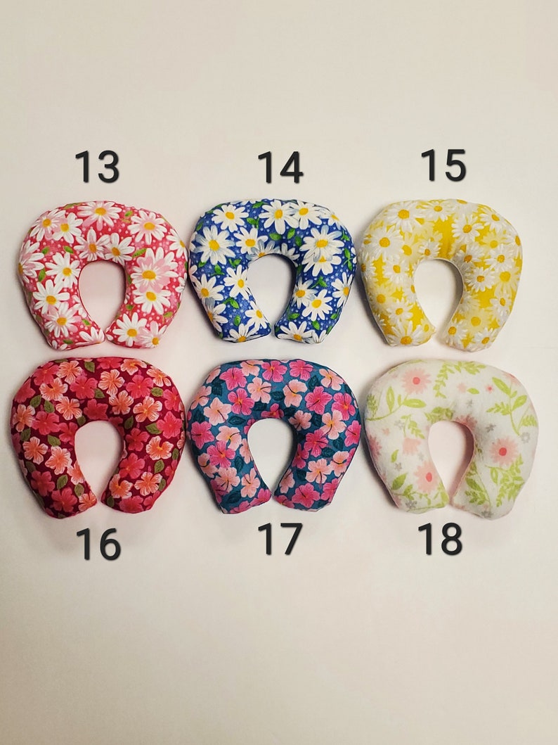 K&ouml;nnte beinhalten: Sechs verschiedene Nackenst&uuml;tzkissen mit Blumenmustern. Die Kissen sind in den folgenden Farben: rosa, blau, gelb, rot, t&uuml;rkis und wei&szlig;. Die Kissen sind von 13 bis 18 nummeriert.
