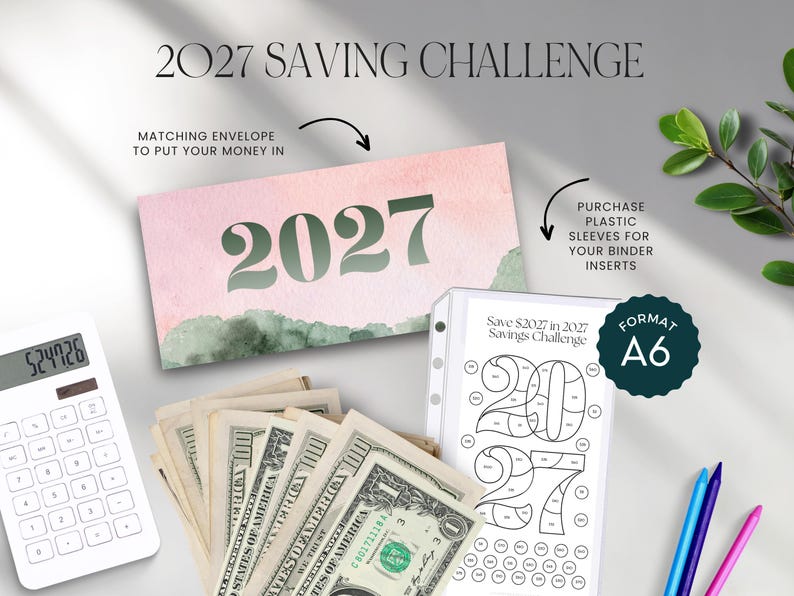 Op de afbeelding: Een 2027-spaaruitdaging-set met een roze en groene aquarelkaart, een witte A6-binderinzet met een 2027-kleurtracker, een witte rekenmachine en een stapel Amerikaanse dollarbiljetten. Tekst: 2027 SAVING CHALLENGE en Save $2027 in 2027.