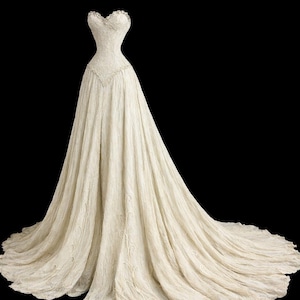 Peut inclure: Robe de mariée ivoire sans bretelles avec un décolleté en cœur et une jupe fluide. Le corsage présente des détails en dentelle délicate, et la jupe se transforme en une longue traîne. La robe est en tissu texturé, créant un look doux et romantique.