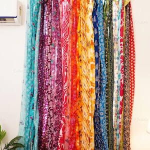 May include: A set of vertical fabric strips in a rainbow of colors and patterns, including teal, magenta, pink, orange, yellow, blue, green, and red, hanging from a horizontal rod. Each strip features distinct floral, geometric, or abstract prints.
