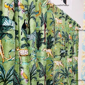 May include: Green velvet fabric with a repeating pattern of zebras, leopards, toucans, and tropical birds. The fabric has a subtle sheen and a soft texture.