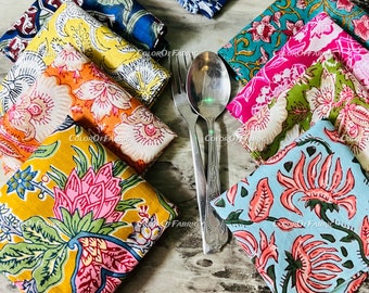 May include: A set of colorful napkins with floral patterns. The napkins are folded and stacked on a wooden surface. The napkins are made of cotton and are perfect for adding a touch of elegance to any table setting.