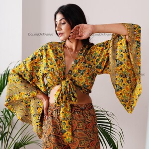 May include: A yellow and green floral print crop top with a tie front and wide bell sleeves. The top is paired with matching yellow and green floral print shorts with a paisley pattern.