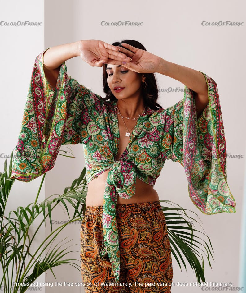 May include: A green and orange paisley print top with long sleeves and a tie front. The top is made of a lightweight fabric and has a relaxed fit.