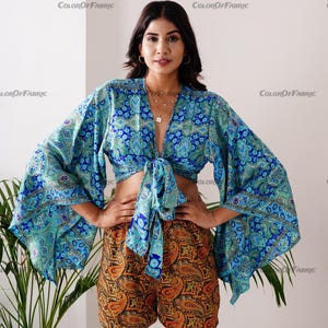 May include: A blue and green patterned crop top with a tie front and matching shorts with a paisley print. The top has long, wide sleeves.