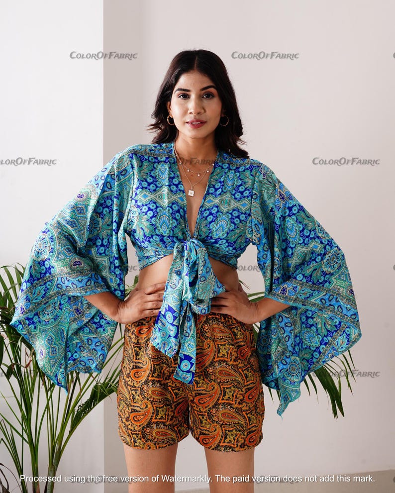 May include: A blue and green patterned crop top with a tie front and matching shorts with a paisley print. The top has long, wide sleeves.