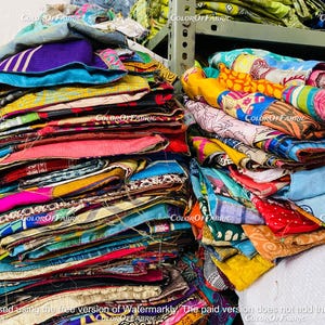 May include: A large stack of colorful fabric scraps, some with patterns, some with solid colors. The fabric is folded and stacked neatly, creating a vibrant and textured display.