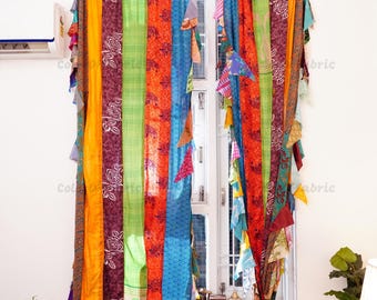 May include: A pair of window curtains made from vertical strips of multicolored fabric. The panels feature a mix of bright orange, lime green, deep purple with white floral patterns, and blue textures, with frayed fabric edges hanging along the sides.