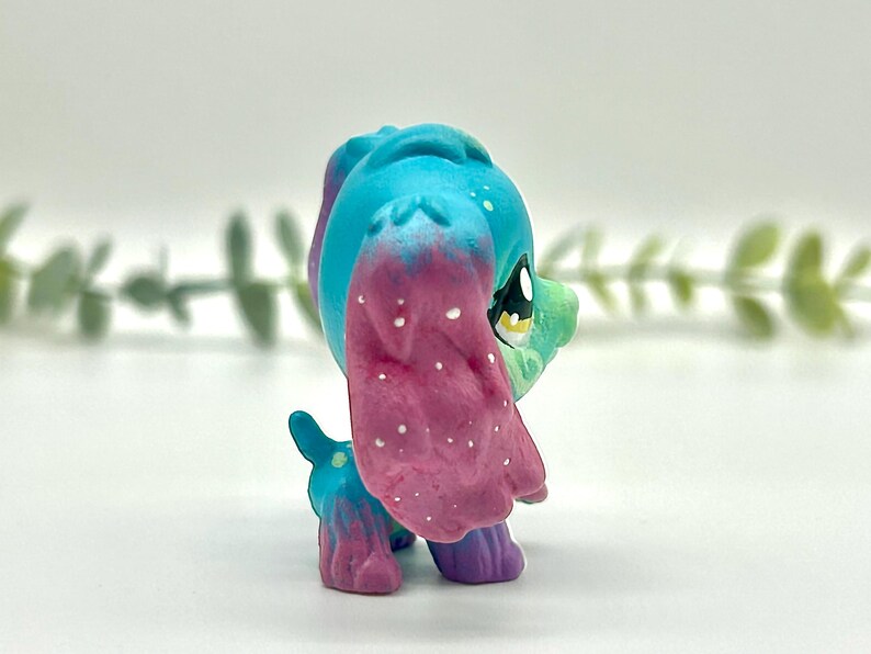 Peut inclure: Figurine de chien jouet color&eacute;e avec une t&ecirc;te et des oreilles bleues, passant au rose avec des mouchetures blanches. Le corps est un m&eacute;lange de bleu, de vert et de violet. C'est un objet de collection.