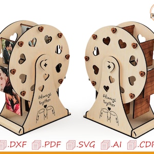 以下が含まれることがあります： ハート型の切り抜きと小さなハートのアクセントが付いた、木製の観覧車のフォトディスプレイ。ベースには「Always Together」の文字とカップルのシルエットが描かれています。ディスプレイにはいくつかの写真が収められています。