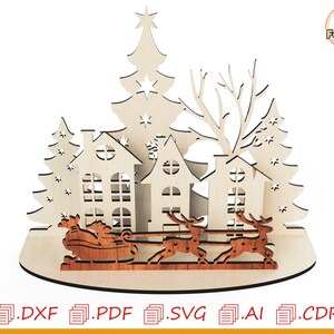 May include: A laser cut wooden Christmas scene with a Christmas tree, houses, and Santa Claus in a sleigh pulled by reindeer. The scene is on a brown base.
