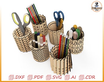 May include: Five wooden pencil holders with different designs. The holders are made of laser-cut wood and feature various patterns, including letters, stripes, and geometric shapes. The holders are filled with pencils, pens, and scissors.